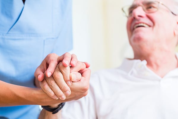 nurse holding hands with a senior man