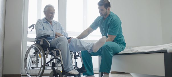 A nurse helps a man in a wheelchair with leg exercises.